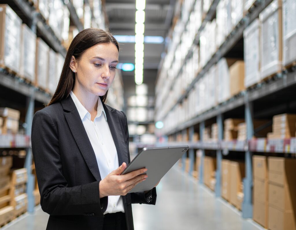A manager overseeing digital tablets displaying inventory metrics in a warehouse - Logistics Buyer